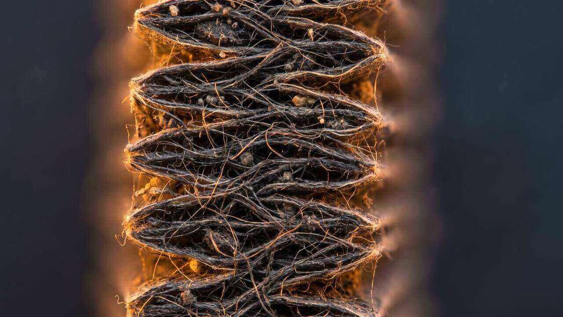 Extreme close-up cross-section of dense pleated HEPA filter media capturing microscopic particles